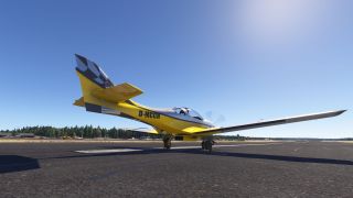 A yellow and gray low-wing propeller aircraft sits on a runway, viewed from behind beneath a clear blue sky.