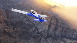 A blue-and-white aircraft with checkered tail markings flies above rugged canyon ridges beneath golden sunlight and scattered clouds.