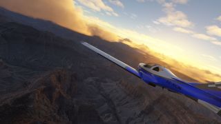 A blue-and-white aircraft marked EC-KCN banks above rugged canyon ridges beneath golden clouds and a partly blue sky.