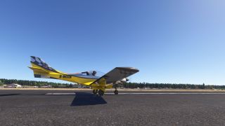 A yellow and black light aircraft sits on the runway with wheel chocks, checkerboard markings, and registration D-MCCH beneath clear skies.