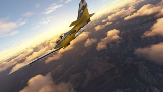 A yellow aircraft with a black-and-white checkered tail banks steeply above rugged canyons and scattered clouds lit by golden sunlight.