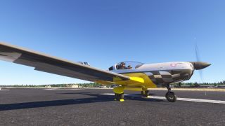 A yellow, white, and black single-engine aircraft sits on pavement with wheel chocks, two cockpit occupants, and a spinning propeller.