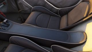 Two padded cockpit seats flank a carbon-fiber-patterned center console, with control levers and a curved control stick visible.