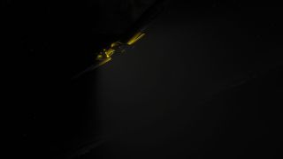 A partially illuminated aircraft crosses a dark, star-speckled sky, with yellow surfaces visible along its diagonally tilted wings.