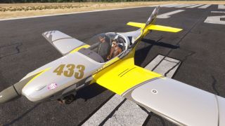 A yellow and silver low-wing aircraft marked 433 sits on a runway with two headset-wearing occupants beneath its clear canopy.
