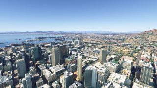 Dense city towers overlook a harbor with cargo ships and cranes, while railway tracks extend inland toward distant hills.