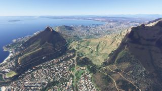 A coastal city spreads between steep mountain slopes and a broad bay, with winding roads, hillside neighborhoods, and harbor docks visible.