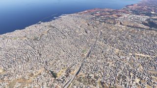 A dense coastal city surrounds a curving highway, with harbor breakwaters and an airport runway visible beside the sea.