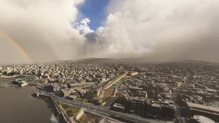 A dense coastal city stretches beneath towering clouds, with a rainbow to the left and fortified walls beside waterfront roads.