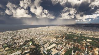 A dense coastal city stretches beneath towering clouds, with rain shafts and a faint rainbow visible over the sea.