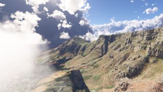 Rocky mountain cliffs rise above a coastal settlement, with scattered vegetation on the slopes and thick clouds partly obscuring the ocean.