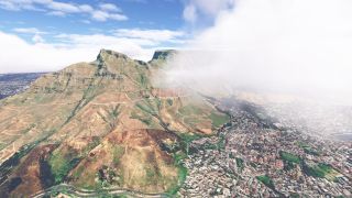 Low clouds partially obscure a flat-topped mountain above dense neighborhoods, while winding trails cross its rocky slopes and a road curves below.