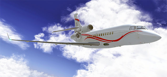 Falcon 7X in flight with clouds in background.