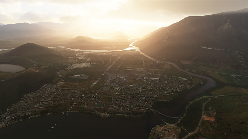 Airport in valley with clouds and sun glare.