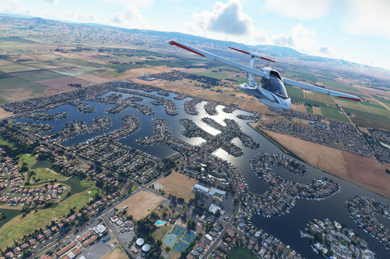 Icon A5 flying over terrain with lakes below and mountains in the distance.